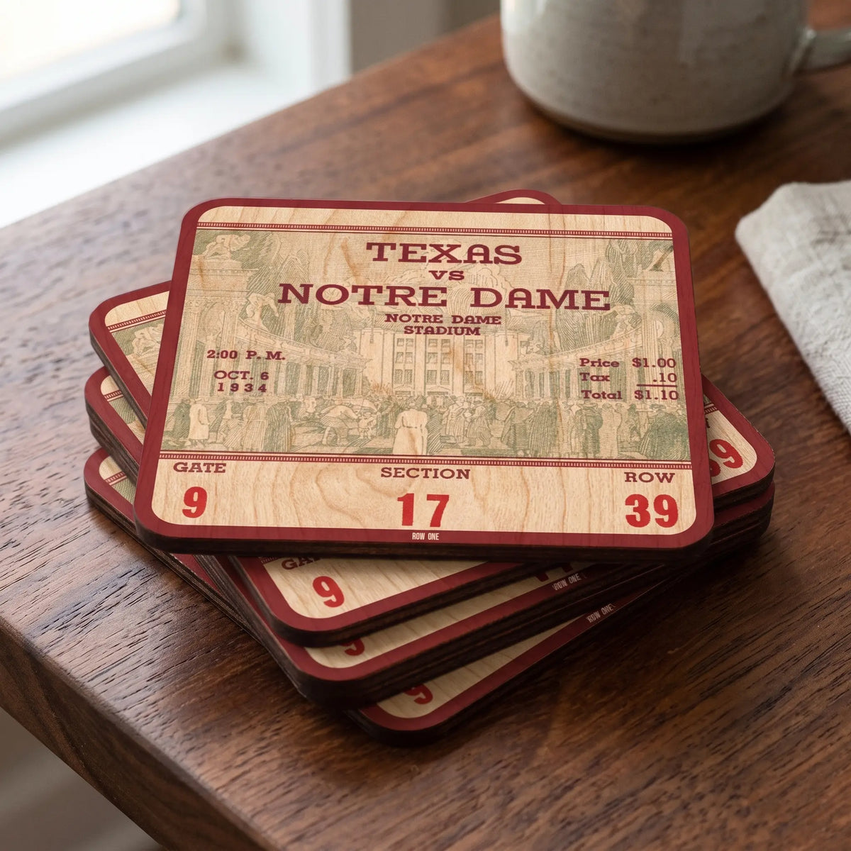 A stack of rectangular coasters designed from a 1934 historic vintage ticket stub, featuring a Texas vs. Notre Dame stadium design, displayed on a wooden table next to a mug.