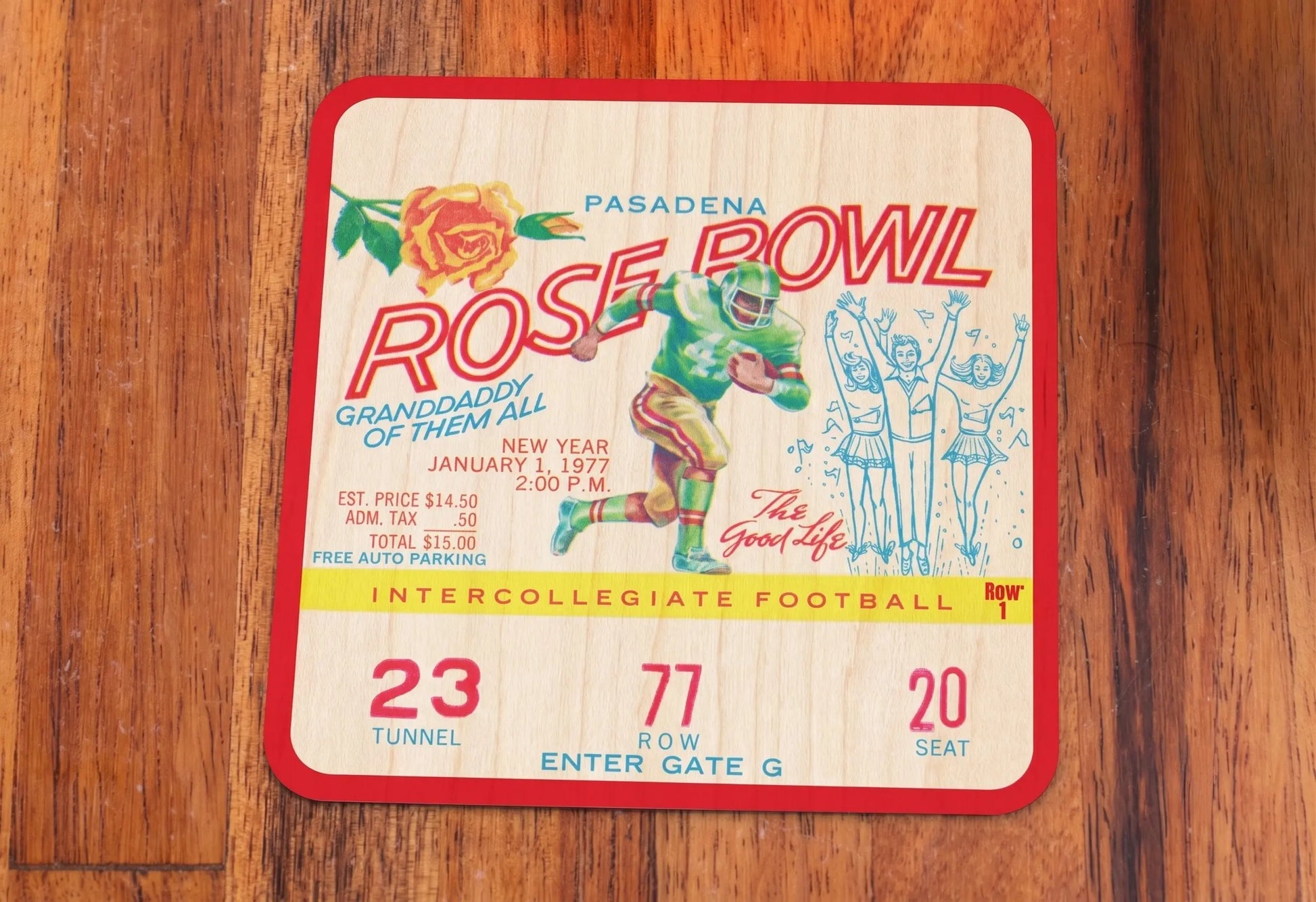A Row One Brand vintage 1977 Pasadena Rose Bowl intercollegiate football ticket with Row 1 trademark printed on a square birch wood coaster, displayed flat on a wooden surface.