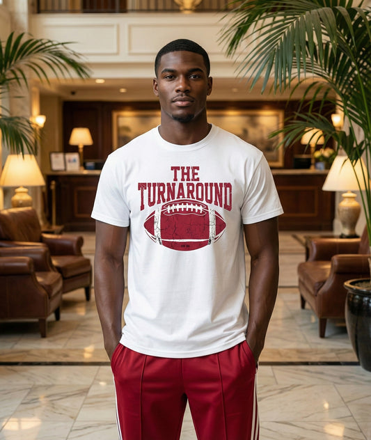 Man wearing a white t-shirt with 'The Turnaround' design in a hotel lobby.