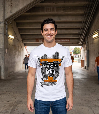 A smiling man wearing a Row One Brand vintage Texas college tee white graphic t-shirt with a longhorn steer and cactus design, standing in a concrete tunnel.