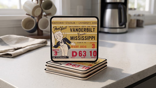 A stack (4) of rectangular birch wood football ticket coasters with rounded corners sits on a kitchen countertop. The top coaster shows a historic 1963 Vanderbilt- Mississippi football ticket design from Row One Brand.