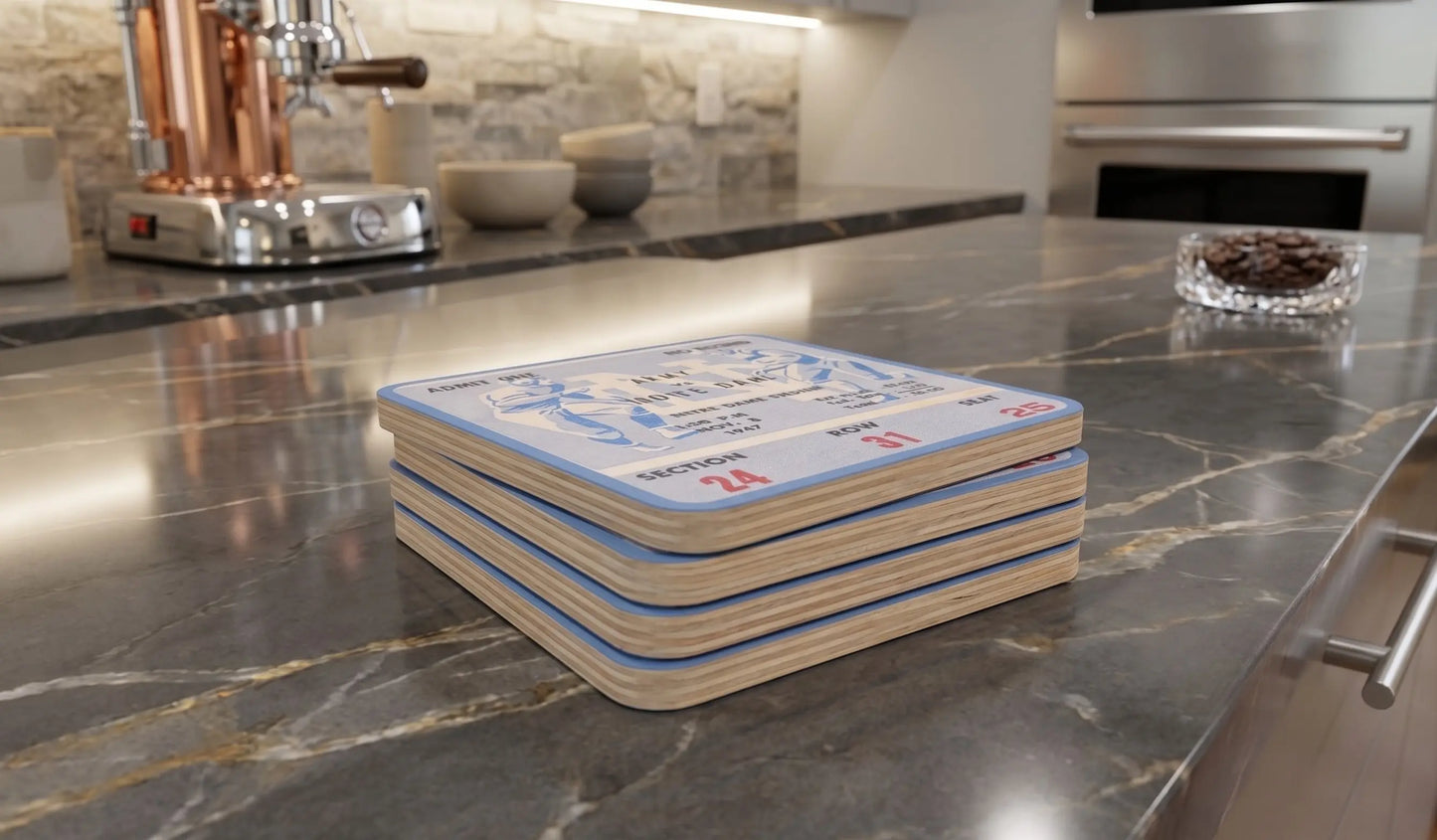 A stack of four Row One Brand square coasters with a  1947 Notre Dame Army football ticket design sits on a polished dark marble kitchen countertop.