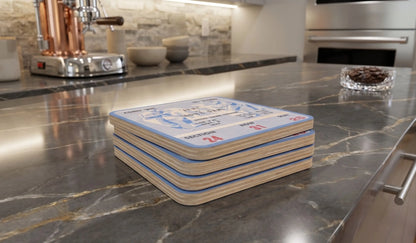 A stack of four Row One Brand square coasters with a  1947 Notre Dame Army football ticket design sits on a polished dark marble kitchen countertop.