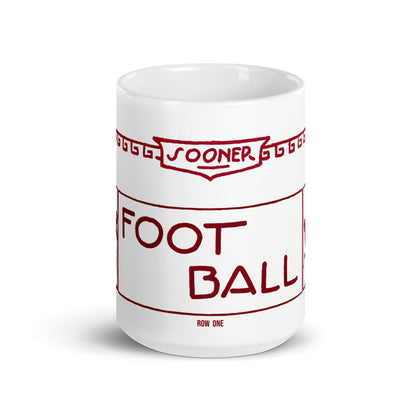 A white ceramic mug featuring a red graphic design styled like a stadium ticket, with the words 'FOOTBALL' and 'ROW ONE' printed on it, set against a plain white background.